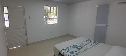 a white room with a bed and a window at Villa Roy in Santa Marta