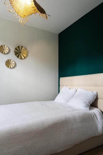 une chambre avec un lit blanc et un mur vert dans l'établissement Appartement chaleureux & confort, parking privé, à Le Teil