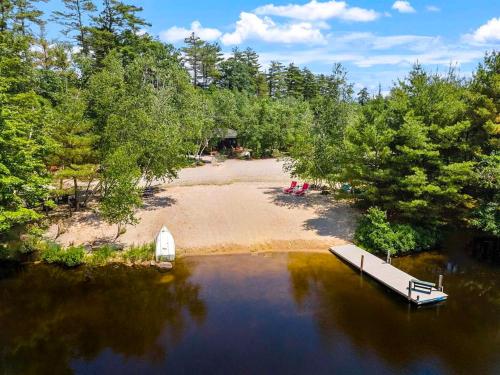 a boat in the water next to a beach at NEW Beautiful Lakefront Home! 500ft of Waterfront! in Wakefield