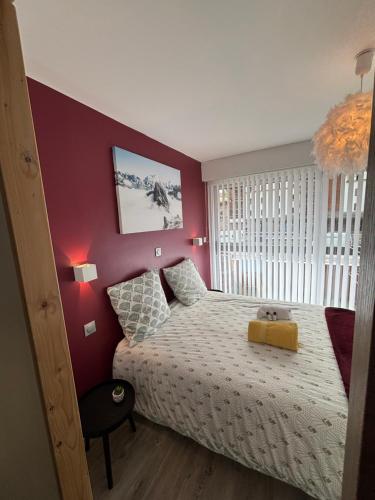 a bedroom with a bed and a red wall at T2 lumineux l' Edelweiss pied du Prorel avec garage privé in Briançon