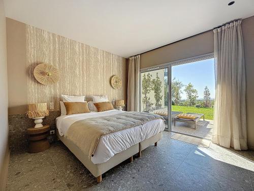une chambre avec un lit et une porte coulissante en verre dans l'établissement Villa Prestige et Vue Mer, à Tourrettes-sur-Loup