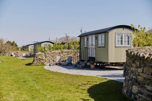 a tiny house in a yard next to a stone wall at Shepherds Huts at The Cornish Arms in Saint Merryn