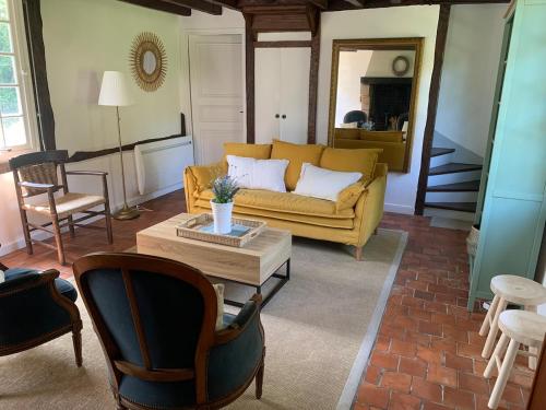 un salon avec un canapé jaune et une table basse dans l'établissement Chaumière du Val, à Triqueville