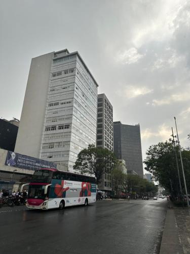a bus is parked in front of a tall building at Departamentos de Lujo Alameda in Mexico City