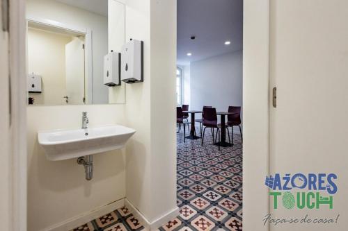 a bathroom with a sink and a table at Hostel Casa São Pedro - Quarto 2 in Angra do Heroísmo