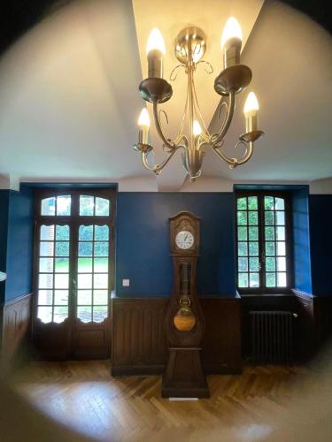 a clock in a room with a chandelier at Manoir Maison Ma Valérie in Castétis