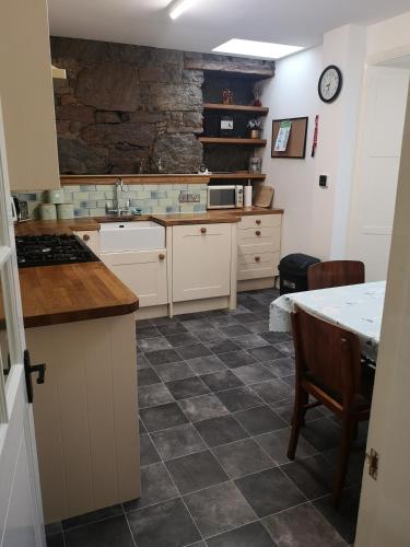 a kitchen with white cabinets and a stone wall at Friars Shott Cottage in Inverness