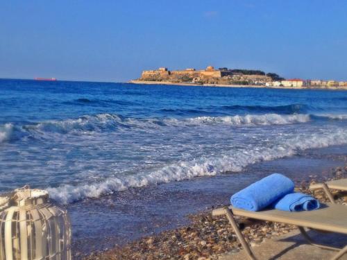 a beach with a chair and the ocean at Filoxenia Beach Hotel in Rethymno Town