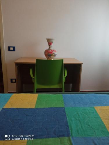 a table and a green chair and a vase on a table at Appartamento al mare in Eraclea Mare