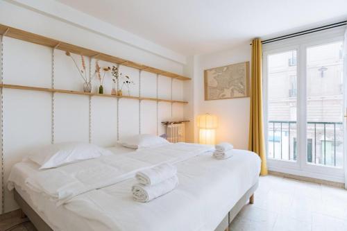 une chambre avec un grand lit blanc avec des serviettes dessus dans l'établissement Flexliving - Beautiful 3-room apartment with living room - 18th, à Paris