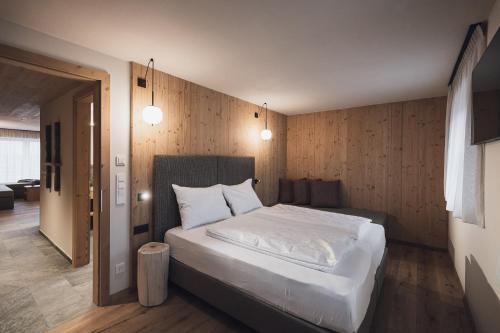 a bedroom with a large bed with white sheets at Kessler's Mountain Lodge in Natz-Schabs