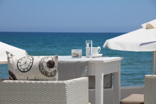 a white table with a pillow on a chair next to the ocean at Filoxenia Beach Hotel in Rethymno Town