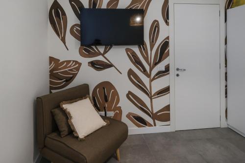 a room with a chair and a tv on a wall at Alma Home Experience in Ventimiglia