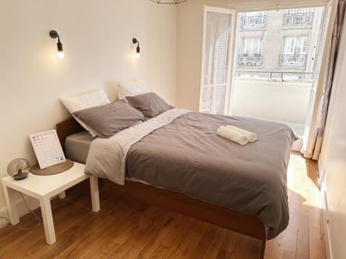 une chambre avec un grand lit avec une fenêtre dans l'établissement T2 with Stunning Balcony 55m2 Paris 17, à Paris