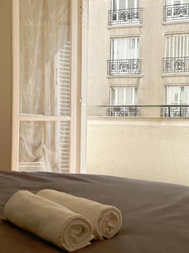 - une serviette posée sur un lit devant une fenêtre dans l'établissement T2 with Stunning Balcony 55m2 Paris 17, à Paris