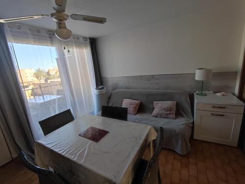 - un salon avec une table, un lit et une fenêtre dans l'établissement Appartement T2 avec piscine, proche de la plage et du Port, à Gruissan