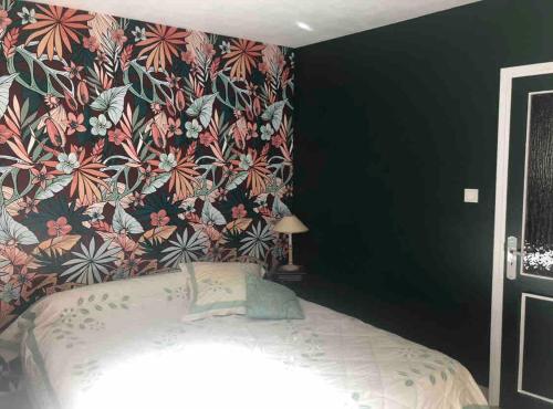 a bedroom with a bed with a floral wallpaper at MAS DUMAS - Maison de village en pierre avec jardin privé in Chandolas