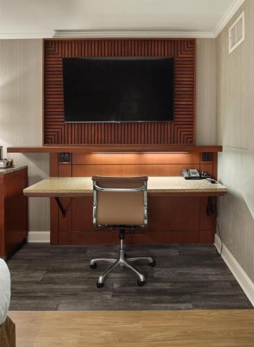 a desk with a chair and a television on a wall at DoubleTree by Hilton Akron Fairlawn in Fairlawn