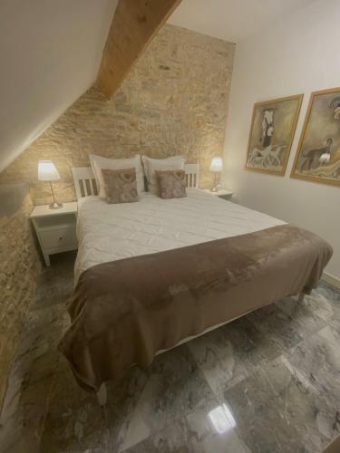 une chambre avec un grand lit et un mur en pierre dans l'établissement Le ROSSIGNOL APPARTEMENT MET AIRCO & PRIVE TERRAS, à Dégagnac