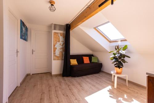 un loft aménagé avec un canapé noir et une fenêtre dans l'établissement Maison entre lac et montagne, à Chorges