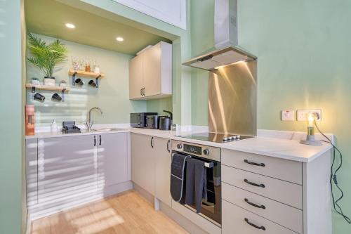 a kitchen with white cabinets and a stove top oven at 3-Bed Flat Free Parking 10 Mins to City Centre in Glasgow