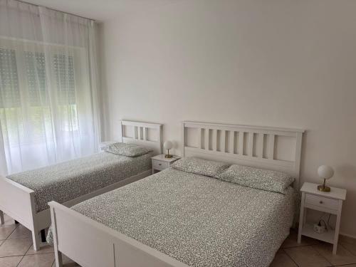 two beds in a bedroom with white walls and windows at appartamento Marciano in Santa Maria di Castellabate