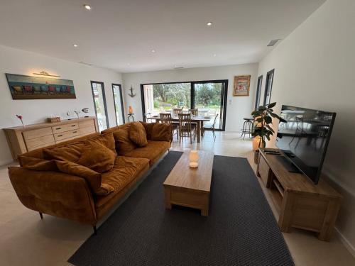 un salon avec un canapé brun et une télévision dans l'établissement VILLA SOULAC ENTRE FORET ET OCEAN, à Soulac-sur-Mer