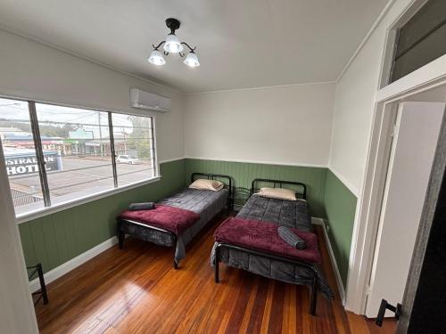 two beds in a room with green and white walls at Tin Town suites in Herberton