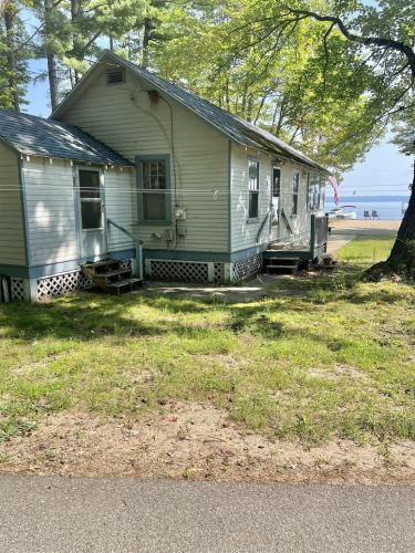 a white house with a porch and a tree at HARMON'S BEACH LIMIT 5 villa in Standish