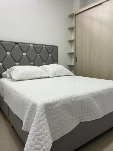 a bedroom with a large bed with white sheets at Apartahotel Centro 101 Edificio PF7 primer piso in Pitalito