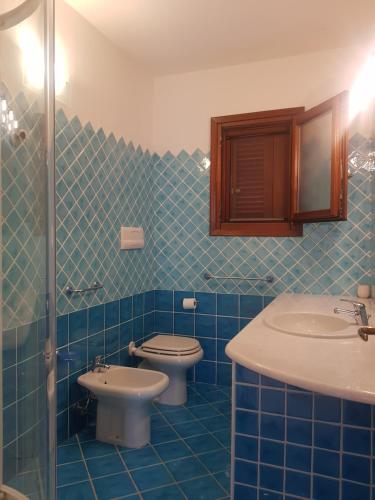 a blue tiled bathroom with two toilets and a sink at Holiday Villa San Teodoro in San Teodoro