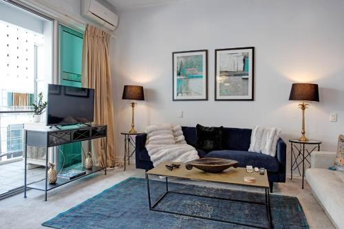 a living room with a couch and a tv at Spacious Newly Renovated Princes Wharf 1BR in Auckland