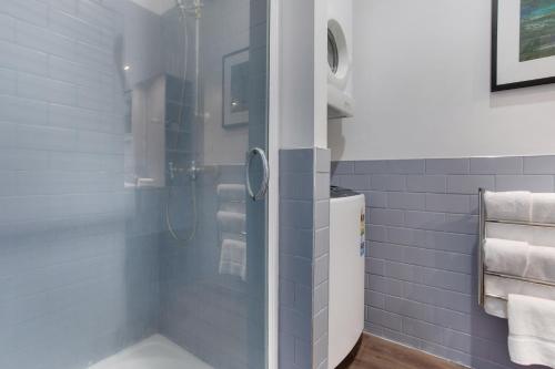 a bathroom with a shower with blue tiles at Spacious Newly Renovated Princes Wharf 1BR in Auckland