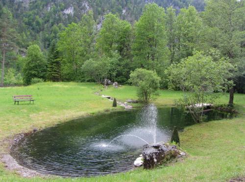 a fountain in a pond in a park with a bench at Hotel Bergkristall in Wildalpen