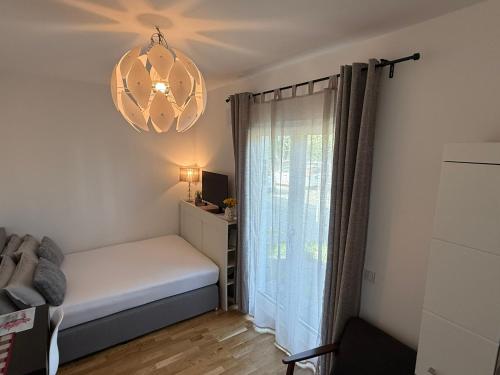 a small bedroom with a bed and a chandelier at Cosy room near Berlin and close to Tesla Factory in Brandenburg in Vogelsdorf