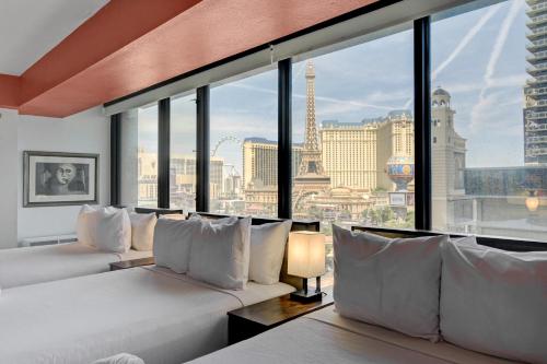 two beds in a room with a view of the eiffel tower at Stay Together Suites - Stunning Penthouse On The Strip Sleeps 16 - NO RESORT FEE in Las Vegas