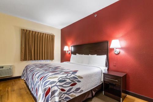 a hotel room with a bed and a red wall at Red Roof Inn Georgetown, IN - Louisville West in Georgetown