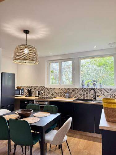 une cuisine avec une table et des chaises noires et des fenêtres dans l'établissement Villa Cornelia Bagnoles Mezzanine Confort & Nature, à Bagnoles-de-l'Orne