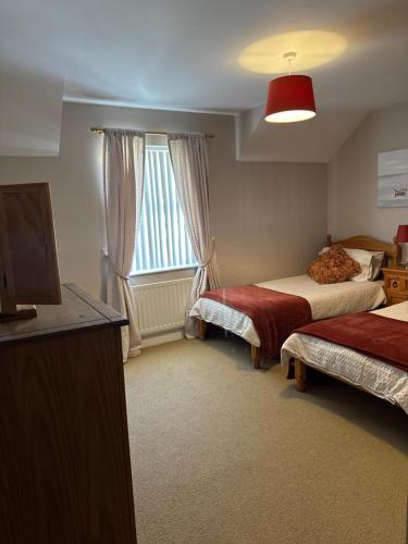 a hotel room with two beds and a television at Pear Tree Cottage, Portstewart in Portstewart