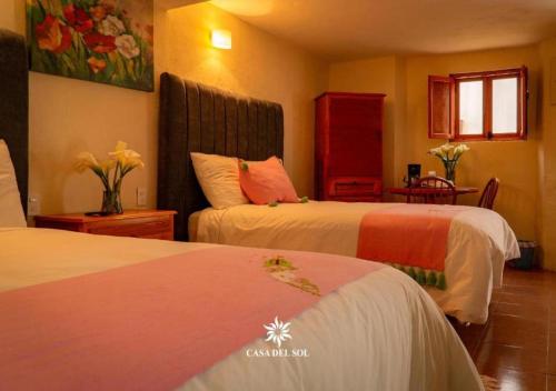 a hotel room with two beds and a table at Hotel Casa del Sol in San Cristóbal de Las Casas
