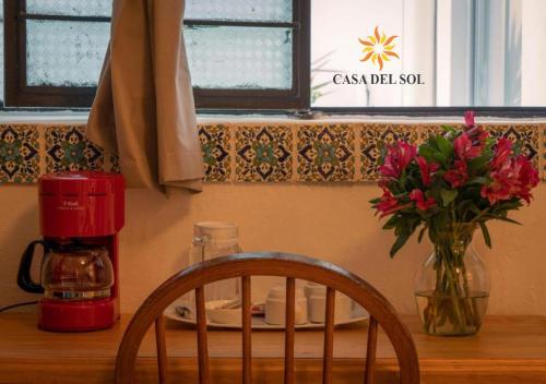 a table with a vase of flowers and a chair at Hotel Casa del Sol in San Cristóbal de Las Casas