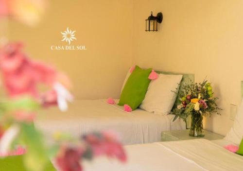 a room with a bed and a vase of flowers at Hotel Casa del Sol in San Cristóbal de Las Casas