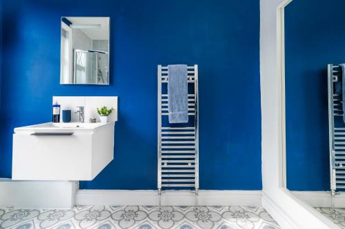 a bathroom with a blue wall with a sink and a mirror at Number 28 - Stylish Town House - 5 bedrooms ALL en suite in Wallasey