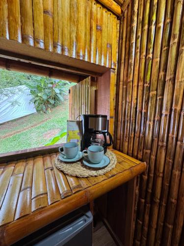 a table with two cups and a coffee maker on it at Hotel Campestre la Playa in Betania