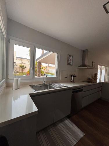 a large kitchen with a sink and two windows at La caprichosa in Chiclana de la Frontera