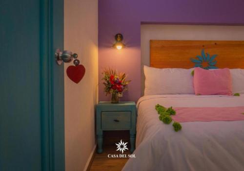 a bedroom with a bed and a vase of flowers on a table at Hotel Casa del Sol in San Cristóbal de Las Casas