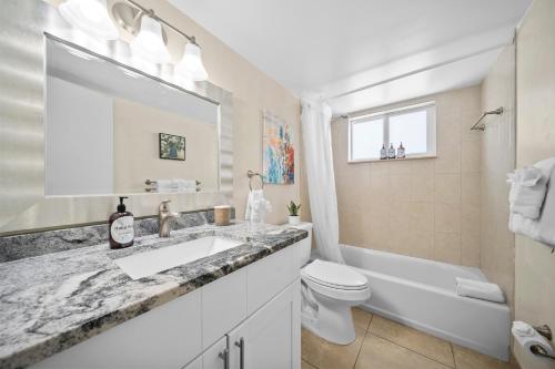 a white bathroom with a sink and a toilet at Coco Palms Apartments By Lowkl in Lighthouse Point
