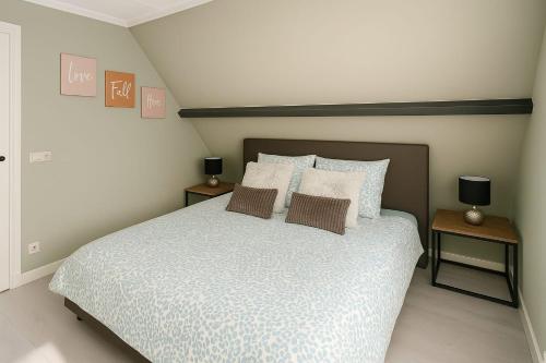 a bedroom with a bed with pillows and two tables at Escape Playero in Breskens