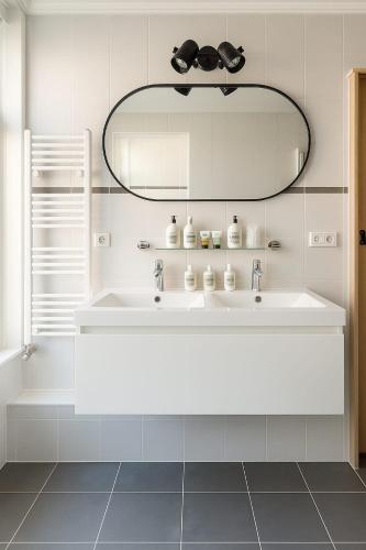 a white bathroom with a sink and a mirror at Escape Playero in Breskens