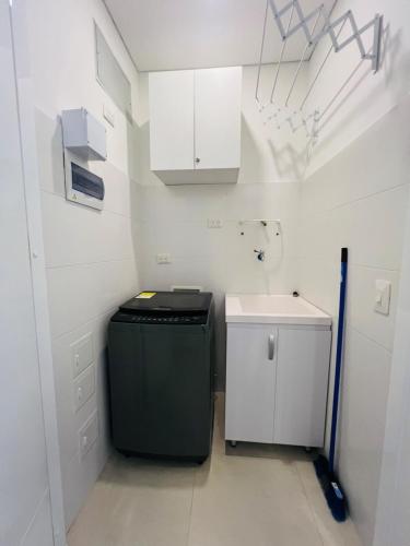 a small kitchen with a refrigerator and a sink at Comfortable apartment near the beach in Playa Bello Horizonte